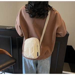 Détail d'un petit sac bandoulière en nylon beige avec étiquette tissée et sangle