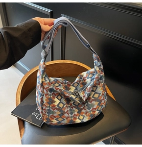 Close-up of geometric knit tote with adjustable blue strap and premium zipper detail
