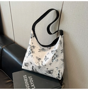 Dettaglio della borsa tote bianca con stampe di farfalle nere e tracolla larga nera