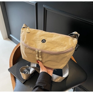 Dettaglio della borsa a tracolla kaki a mezzaluna con logo JL su una sedia moderna