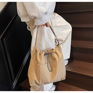 Detail of khaki drawstring bucket bag with dual front pockets and textured nylon fabric