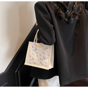 Floral canvas tote with wooden button and rope handle shown on black blazer