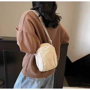 Gros plan d'un mini sac bandoulière crème montrant la texture et l'effet porté sur soi