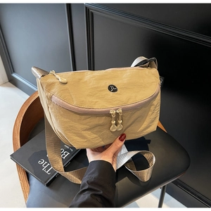 Dettaglio macro della borsa a tracolla in nylon kaki con tasca a zip e tracolla in tessuto