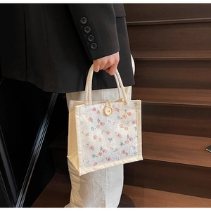Floral lace tote bag detail with thick rope handles and vintage wood button closure