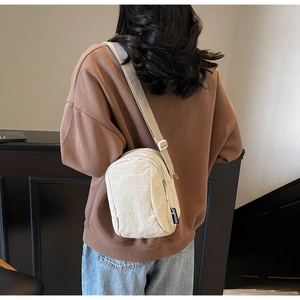 Vue détaillée du sac bandoulière en nylon crème avec sangle réglable sur un mannequin