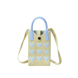 Knitted heart pattern crossbody bag with round blue handles on yellow crochet base