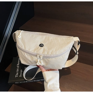 Dettaglio della borsa a tracolla in nylon bianco sporco con tasche multiple su legno