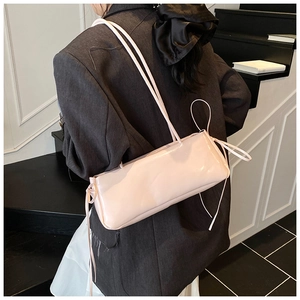 Detail of light pink patent leather underarm bag with slim straps on a model in stairs