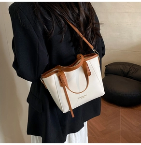 Detail van de crème lederen bucket bag met bruine handvatten en merktekst print