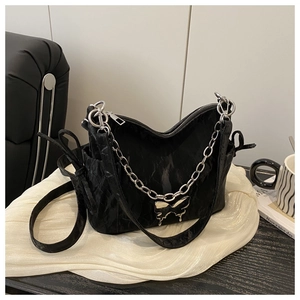Détail du sac bandoulière plissé noir avec breloque papillon et chaîne argentée