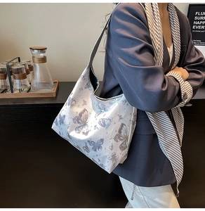 Dettaglio della borsa tote bianca con stampe di farfalle viola e pelle lucida