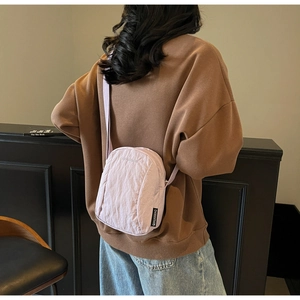 Détail du mini sac bandoulière lilas en nylon avec logo gaufré et étiquette tissée