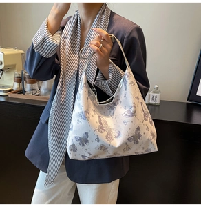 Dettaglio della borsa hobo bianca con motivo a farfalla viola indossata da una modella