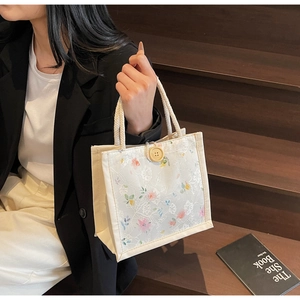 Detail of white lace handbag with floral embroidery and wooden button closure