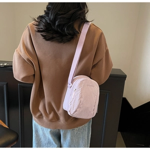 Vue détaillée du petit sac bandoulière en nylon violet porté par un mannequin pour la taille