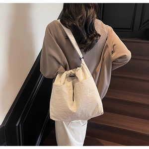 Detailed back view of a minimalist cream drawstring bucket bag with side pockets on model