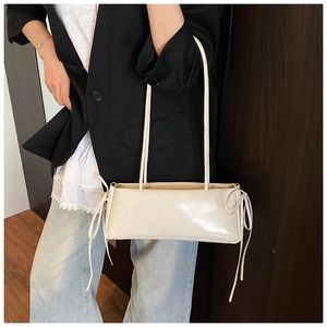 Detail of cream pillow bag with cute side bow accents and slim leather shoulder strap
