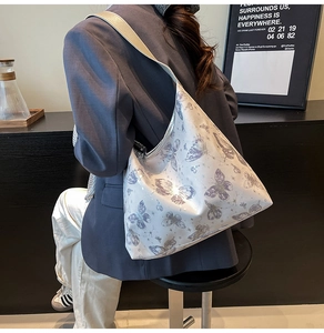 Dettaglio della borsa tote bianca capiente con farfalle viola e tracolla larga in grigio