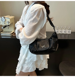 Gros plan d'un sac bandoulière noir texturé avec boucle nœud en argent et bandoulière en cuir