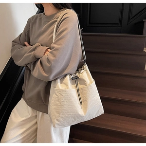 Close-up of the beige drawstring bucket bag with textured fabric and side pocket detail