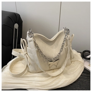 Détail du sac bandoulière blanc crème avec chaîne argentée et ornements de nœuds
