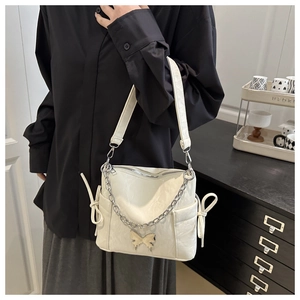 Détail du sac en similicuir plissé blanc crème avec breloque papillon argentée et chaîne