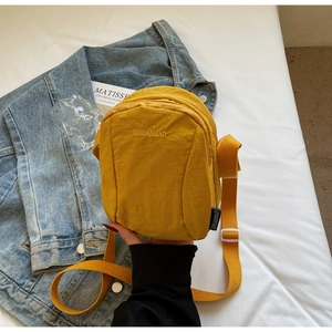 Détail d'un sac bandoulière jaune vif en nylon imperméable avec boucle de réglage blanche