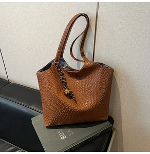Gros plan sur la texture d'un sac cabas marron tissé avec pendentif sphère métal