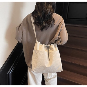 Detail of off-white drawstring canvas tote bag with large double front pockets on a model