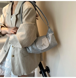 Détail du nœud argenté sur le sac à bandoulière métallisé mat porté par un mannequin