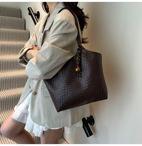 Détail du sac cabas marron foncé avec texture serpent et breloque sphérique dorée