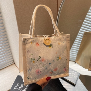 Floral lace canvas handbag with wooden button and woven rope handle in warm indoor setting