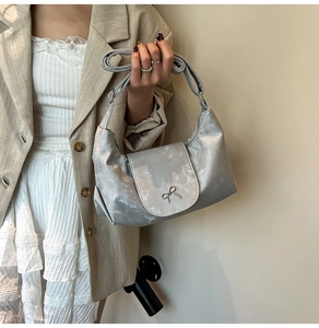Détail du sac argenté métallisé avec nœud porté par un mannequin en tailleur chic