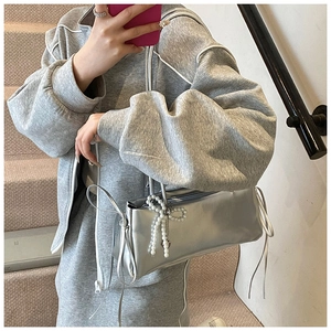 Detail of silver metallic bag with pearl bow charm and long tassel accents for women