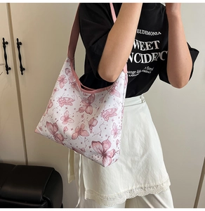 Dettaglio dei motivi a farfalla rosa su borsa tote in tela bianca con ampia tracolla rosa