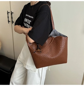 Gros plan du sac cabas marron tissé montrant la texture et l'ornement latéral