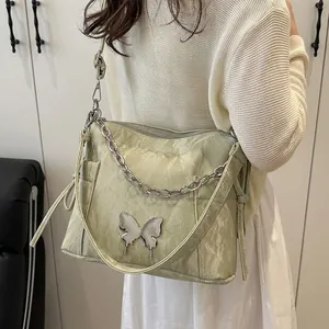Sac bandoulière vert clair plissé avec boucle papillon porté par un modèle