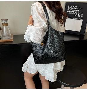 Détail du sac cabas en cuir tressé noir avec fines lanières porté par un mannequin