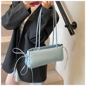 Close-up of light blue shoulder bag with drawstring detail on a leather pillow bag