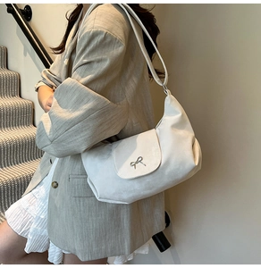 Gros plan du sac hobo beige en similicuir souple avec un nœud en métal argenté