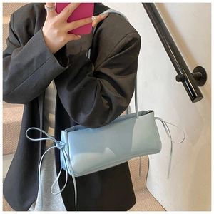 Light blue faux leather underarm bag featuring decorative side ribbons on shoulder strap