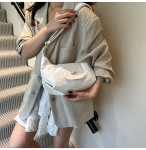 Détail d'un sac à bandoulière en cuir blanc avec une boucle en métal argenté en nœud