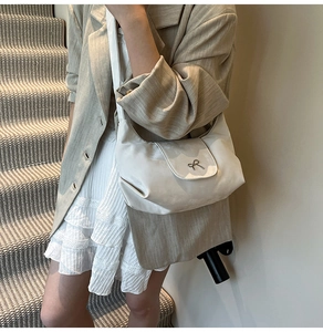 Détail d'un sac bandoulière ivoire en tissu satiné avec nœud métallique élégant