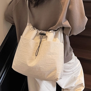 Minimalist beige nylon drawstring bucket bag with dual front pockets for casual commuting