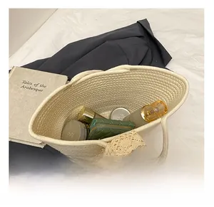 Interior view showing capacity of off-white woven tote bag with cosmetics and wallet