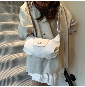 Détail du sac bandoulière crème en demi-lune avec boucle nœud porté par un mannequin