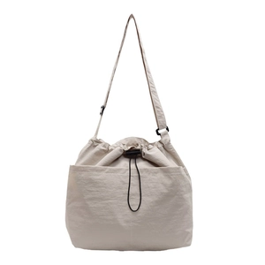 Minimalist beige nylon drawstring bucket bag with adjustable shoulder strap and large pocket