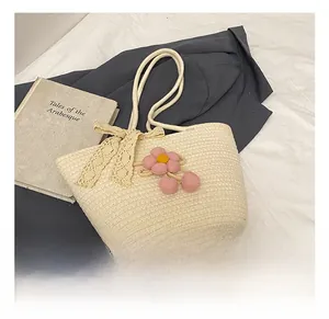 Detailed close-up of handmade woven straw bag with lace bow and pink crochet floral charm