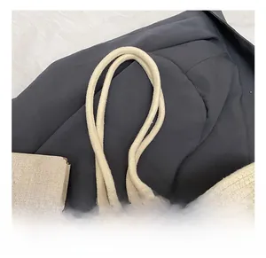 Close-up of the woven cylindrical handles on a beige handmade floral bucket handbag